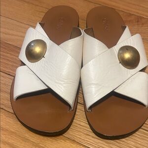 Chloe White Leather Cross-Strap Slide Sandals with Gold Button detail.